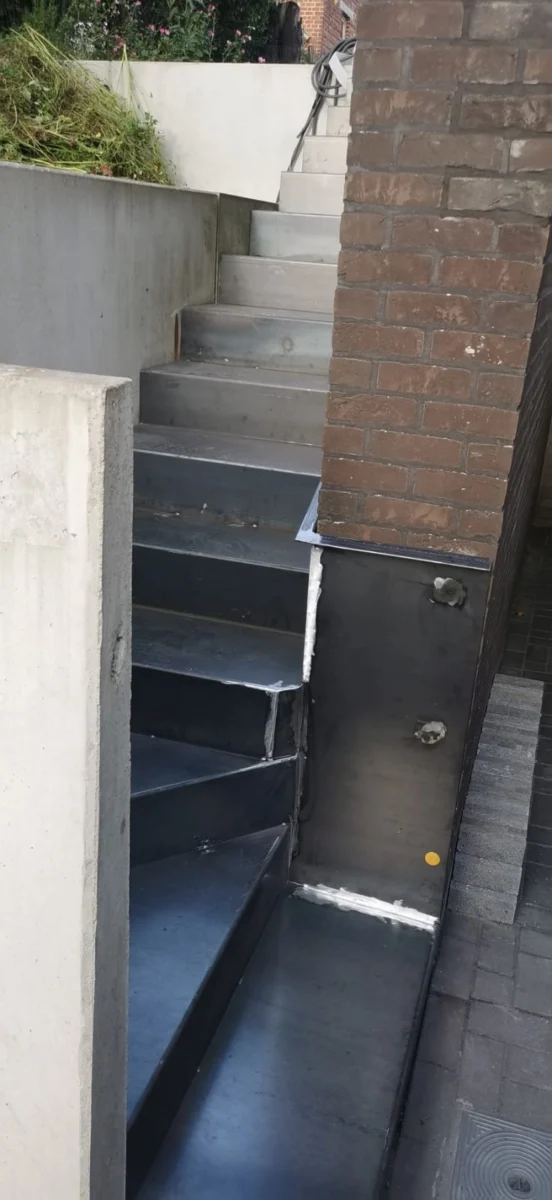 Buitentrap in ruw staal bij de plaatsing langs de gevel