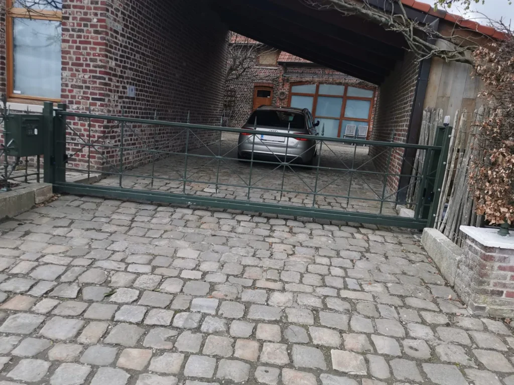 Groen gelakte schuifpoort aan een oprit met kasseien