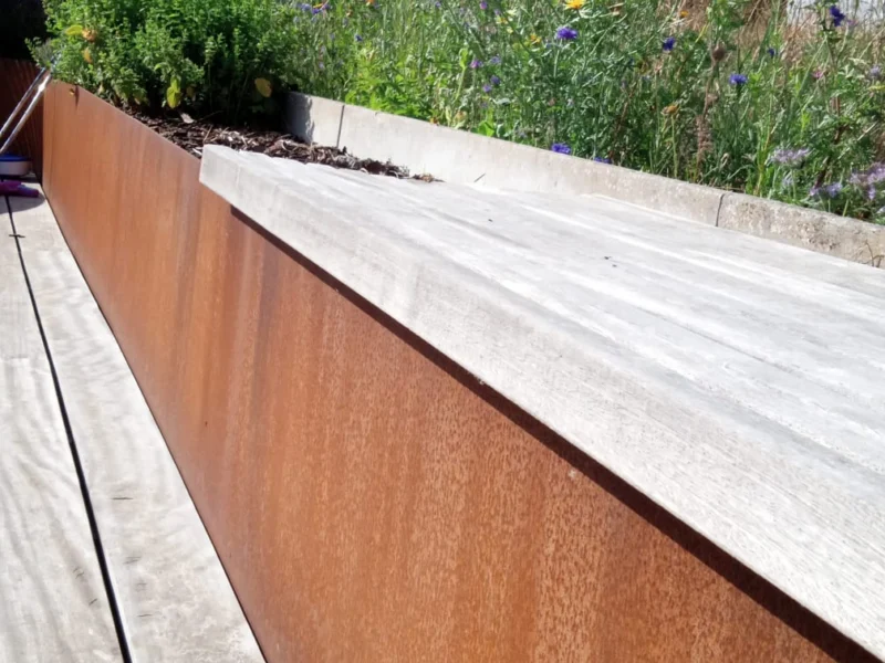 Keerwand in cortenstaal langs een houten terras