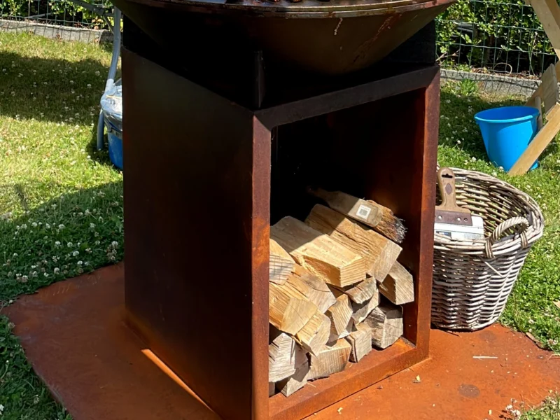 Cortenstaal BBQ met bakplaat en houtopslag op een bodemplaat in cortenstaal in de tuin