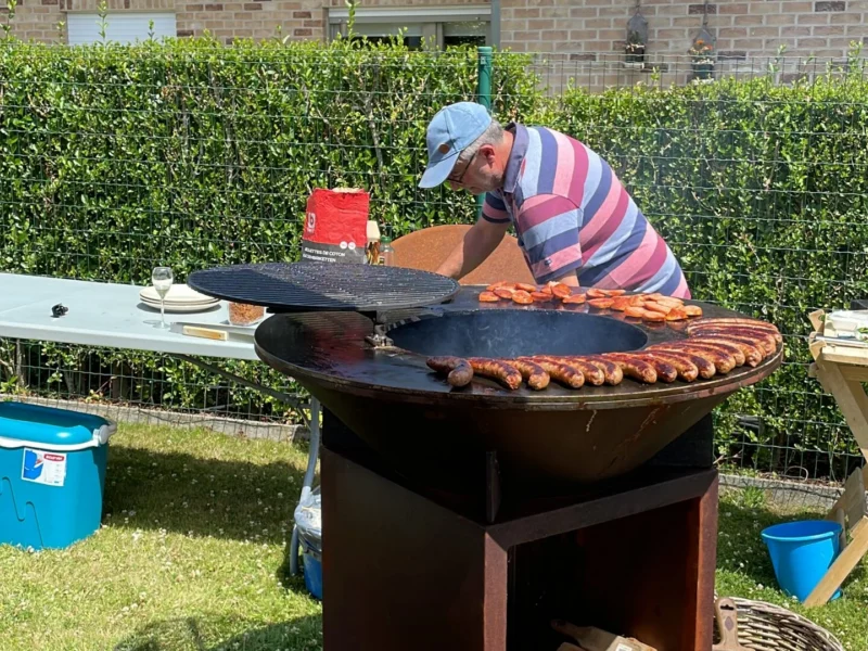 Cortenstaal BBQ met bakplaat en houtopslag in gebruik in de tuin