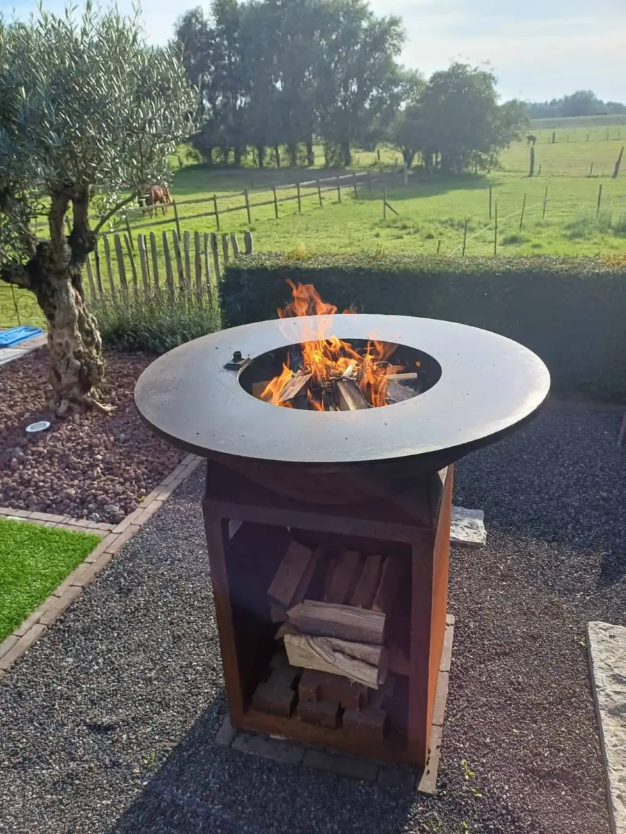 Brandende cortenstaal BBQ met bakplaat rond de vuurschaal in de tuin
