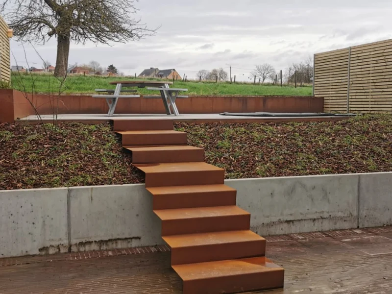 Tuintrap in cortenstaal tussen betonnen keerwanden, overzicht van de tuin