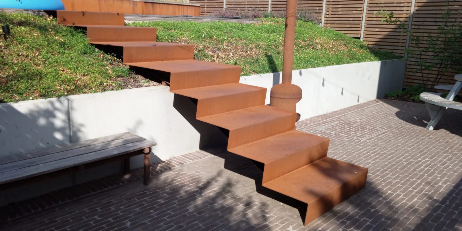 Zwevende tuintrap in cortenstaal tussen terras en hoger gelegen tuin